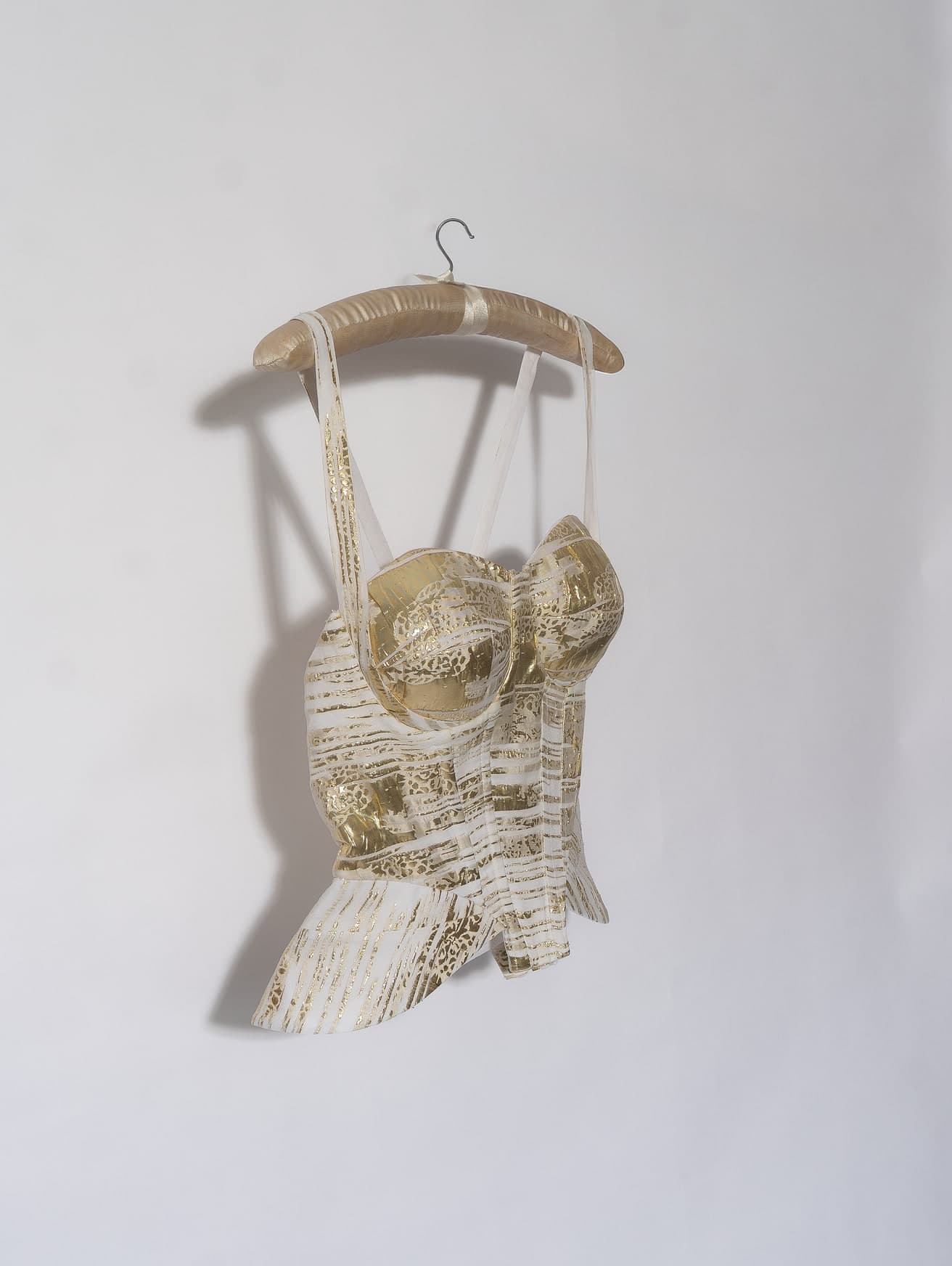 Amari corset top on a hanger, showing the peplum and the gold foil pattern