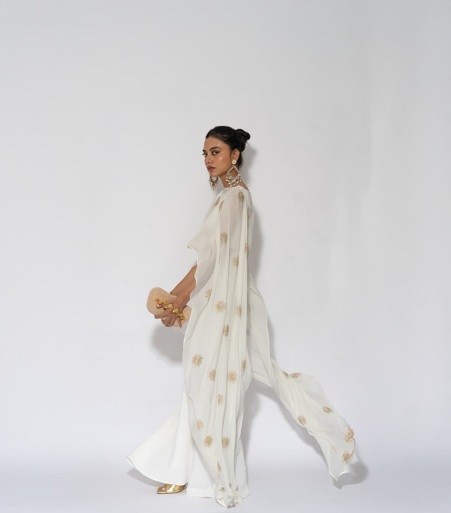 Leela campaign — the Sol set in ivory, walking, the embroidered cape trailing behind