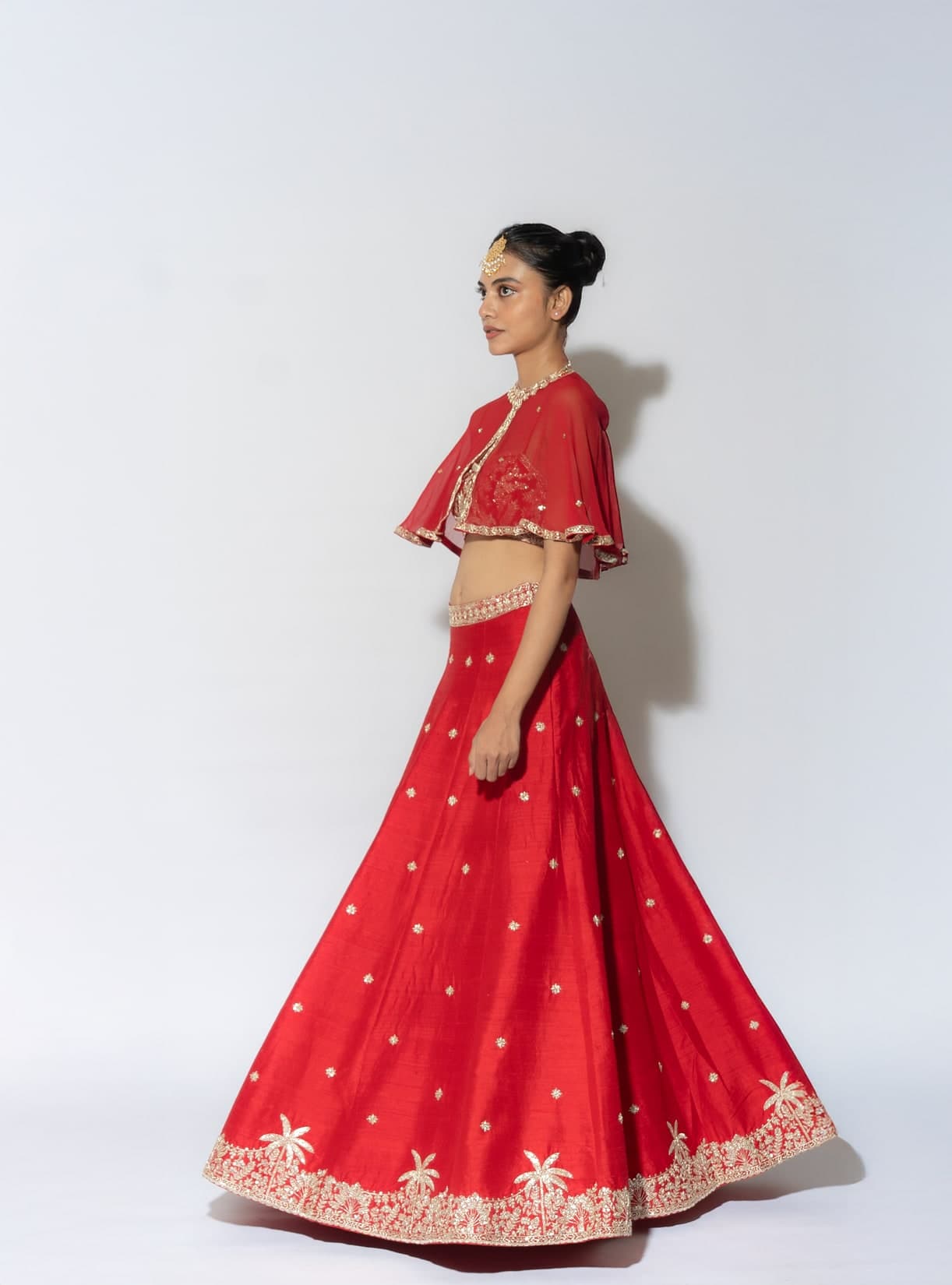 Arya lehenga in red, side view showing the full sweep of the kali skirt and its embroidered hem