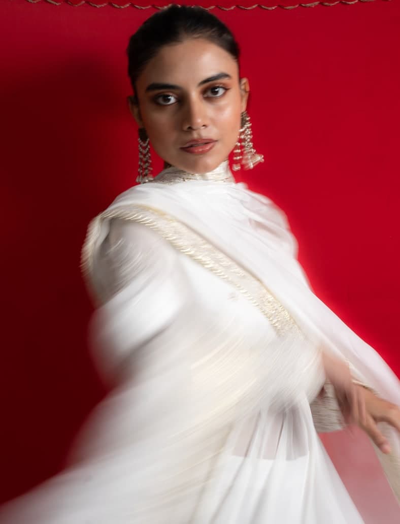 Tara anarkali in ivory, the dupatta draped, photographed against a red ground