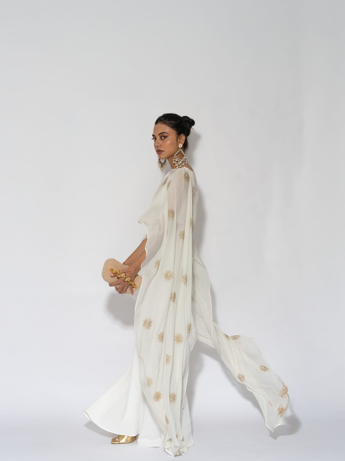 Leela campaign — the Sol set in ivory, walking, the embroidered cape trailing behind