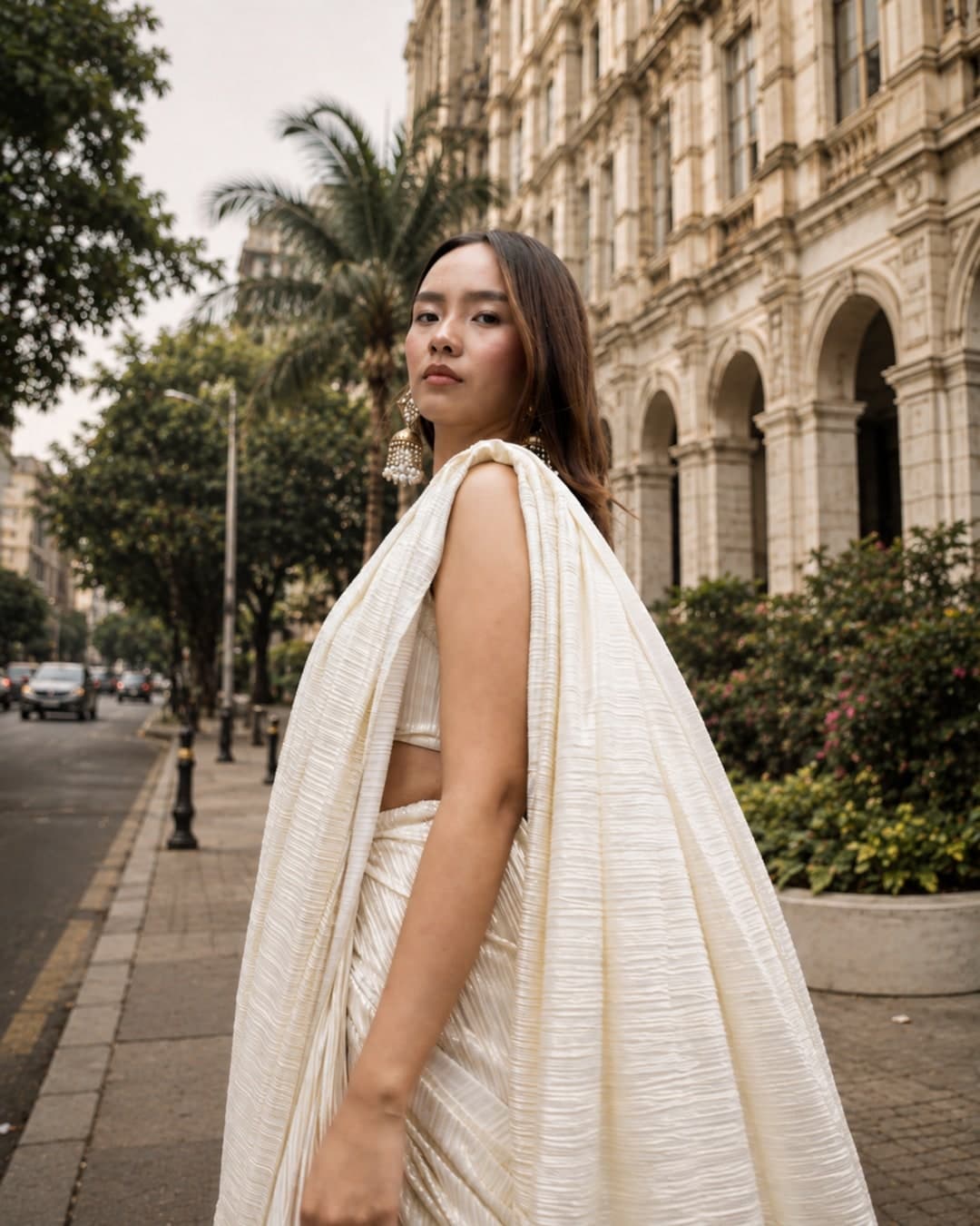 Gigi saree in ivory and gold, full length against a stone wall, showing the fringed pallu